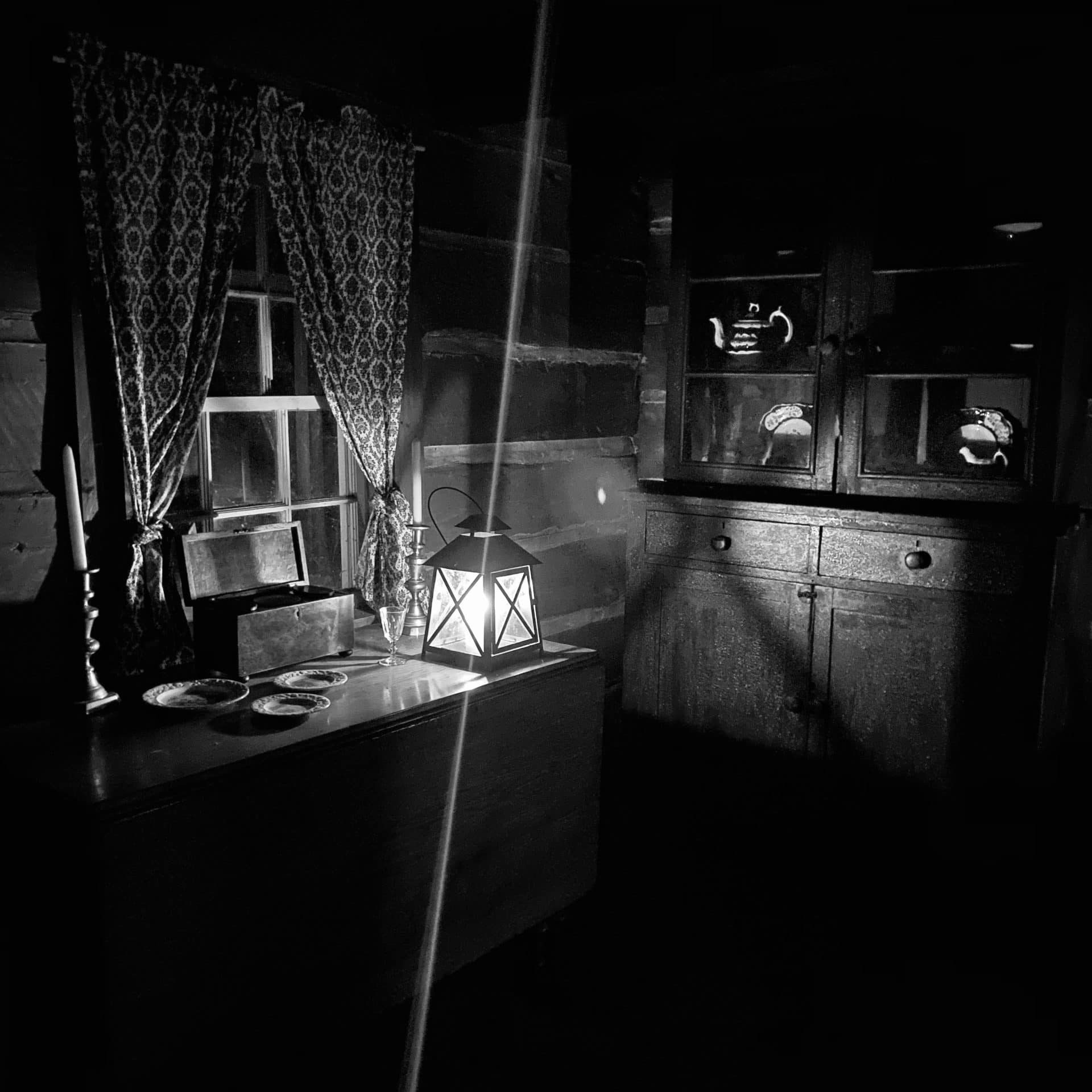 Spooky lantern sitting on a desk in an old fashioned room.